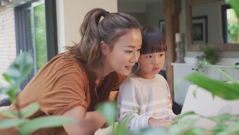 Asiatische-Mutter-hilft-zu-Hause-Schulbildung-Sohn-arbeiten-am-Tisch-in-Küche-auf-Laptop