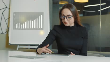 woman-working-with-tablet-in-the-office.-The-business-lady-solves-strategic-tasks-of-the-company-working-alone-in-a-small-office