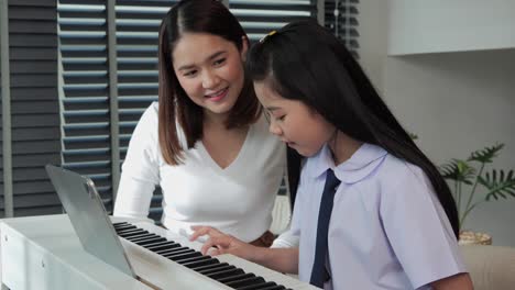 Hermosa-madre-mirando-a-su-hija-tocando-el-piano-en-casa.-Estaba-encantada-de-que-su-hija-pudiera-tocar-el-piano.