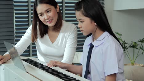 Beautiful-mother-looking-her-daughter-playing-piano-at-home.-She-was-delighted-that-her-daughter-could-play-the-piano.