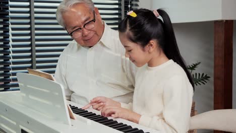 Grandfather-looking-granddaughter-playing-piano-at-living-room.-She-was-showing-play-piano-to-Grandfather-with-confident.