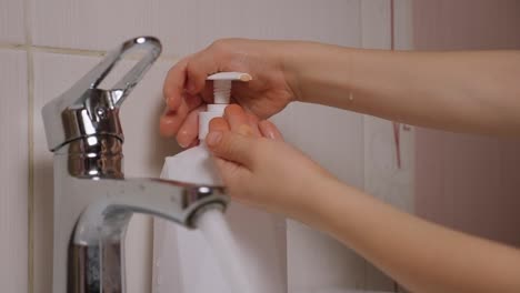 Primer-plano-de-un-niño-pequeño-lavándose-las-manos-con-agua-y-jabón-en-el-baño.