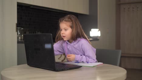 Chica-caucásica-estudiando-en-línea-a-través-de-Internet-en-un-ordenador-portátil-sentado-en-casa-en-la-cocina.-dobla-los-dedos-para-aprender-a-contar.-Concepto-de-aprendizaje-en-línea