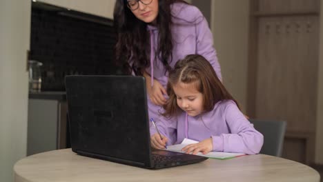 colegiala-ocupada-con-la-escritura,-mirando-la-computadora-portátil-mientras-estudia-en-casa-sobre-coronavirus---concepto-de-aprendizaje-electrónico-de-los-niños,-aula-virtual-durante-la-pandemia-covid-19.