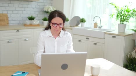 Young-woman-girl-student-freelancer-businesswoman-working,-typing-text-on-keyboard-using-laptop-computer-at-home-kitchen