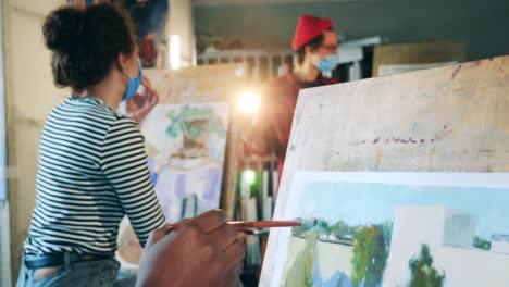 Students-are-painting-during-art-class-with-a-teacher-in-a-face-mask