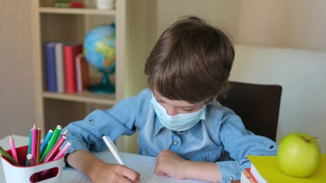Niño-niño-niño-colegial-con-máscara-médica-protectora-aprendiendo-tareas-de-escritura-en-casa