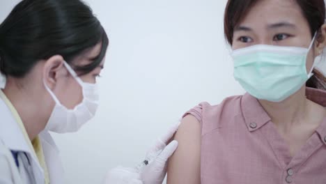Médico-femenino-vacunando-a-la-paciente-para-prevenir-la-propagación-de-la-enfermedad.