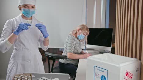 Enfermera-prepara-dosis-de-vacuna-para-vacunación-o-inyección-de-coronavirus-para-una-anciana-en-la-sala-de-vacunación-del-hospital