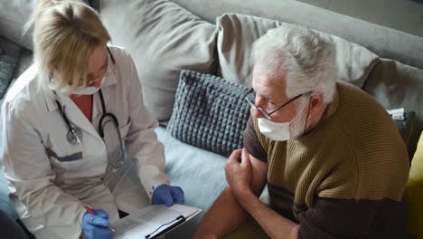 El-médico-rellena-la-documentación-después-de-vacunar-al-abuelo.-Personas-mayores-en-la-vanguardia-de-la-vacunación-COVID-19