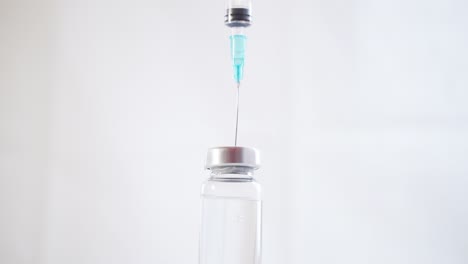 Nahaufnahme-einer-Spritze-mit-einer-Nadel,-die-ein-Medikament-aus-einer-Glasflasche-zeichnet
