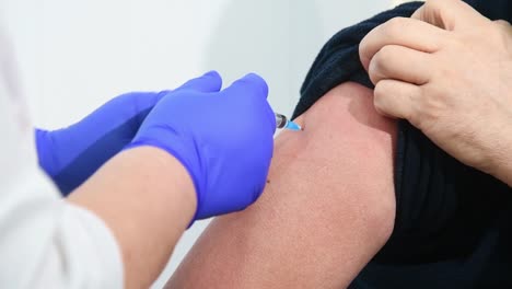 El-médico-inyecta-la-vacuna-contra-la-gripe,-la-neumonía-o-el-COVID-19-en-el-hombro-del-paciente