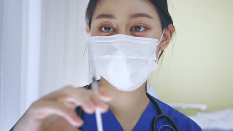 Close-up-of-female-Asian-doctor-holding-a-vaccine-injection-needle-ready-for-vaccination.-Young-medical-lab-technicia-at-work