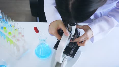 Woman-looking-through-microscope-in-lab