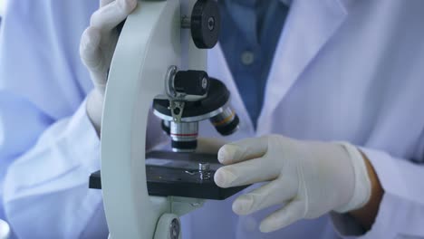 Woman-looking-through-microscope-in-lab