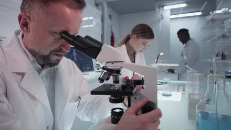 Diversos-científicos-estudiando-muestras-médicas.-Uso-de-computadoras-y-microscopios.-Interior-de-laboratorio-moderno