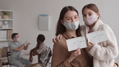 Madre-e-hija-mostrando-tarjetas-de-vacunación