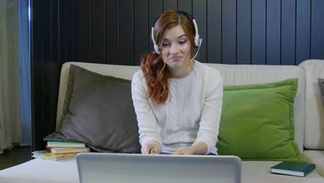 Young-Smiling-Student-Wearing-Headphones-Communicating-By-Video-Call-Doing-Distant-Chat-Working-From-Home.