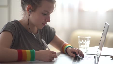 Junge-Schülerin-hat-eine-Online-Lektion-aus-der-Ferne.-Mädchen-sprechen-mit-Kopfhörer-und-Laptop,-Video-Anruf-Konzept