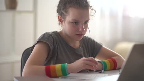 Junge-Schülerin-hat-eine-Online-Lektion-aus-der-Ferne.-Mädchen-sprechen-mit-Kopfhörer-und-Laptop,-Video-Anruf-Konzept