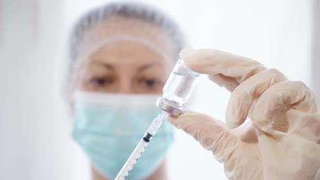 Female-Doctor-Pouring-Medicine-Into-Syringe-From-Glass-Bottle