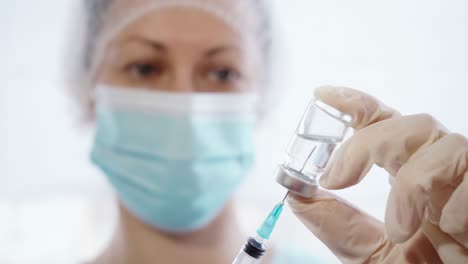 Female-Doctor-Pouring-Medicine-Into-Syringe-From-Glass-Bottle