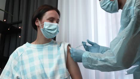 La-joven-está-recibiendo-la-vacuna-covid-29-de-coronavirus-del-médico-de-la-clínica.-Vacuna-contra-el-coronavirus.-Doctor-en-guantes-médicos-que-sostienen-jeringa-con-vacuna-de-2019-nCoV.-Inyección-de-vacunas