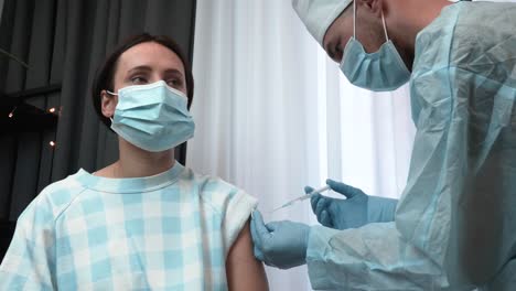 Der-Arzt-in-medizinischer-Schutzkleidung,-Maske-und-Handschuhen-verabreicht-den-Patienten-in-der-Gesundheitsklinik-den-Impfstoff.-COVID-19-Impfung.-Impfstoff-gegen-Coronavirus