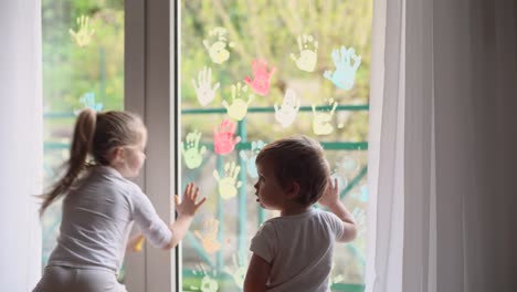 Los-niños-pintan-con-palmas-en-la-ventana.-Cuarentena