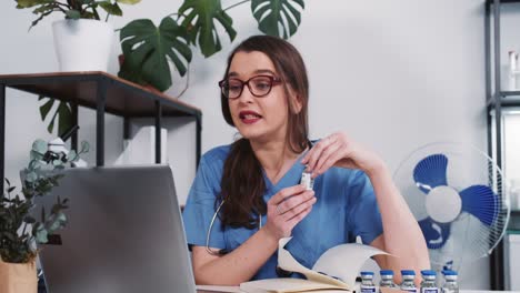 Junge-schöne-kaukasische-Arzt-Frau-in-blau-Krankenschwester-Uniform-bietet-Impfstoff-an-Remote-Patienten-online-über-Laptop-Webcam.