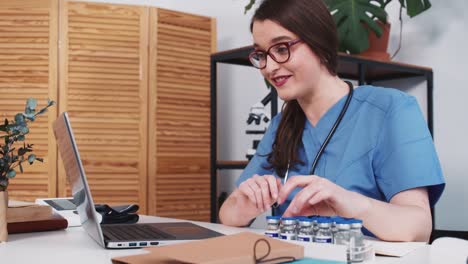 Doctor-working-online.-Happy-female-healthcare-professional-in-blue-uniform-offers-vaccine-to-remote-patient-on-webcam.