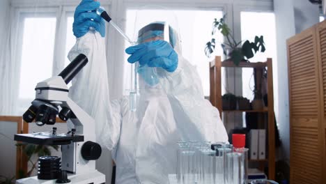 Young-focused-female-chemical-lab-scientist-doctor-in-white-medical-protection-suit-works-on-new-coronavirus-vaccine.