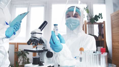 Hope-in-fighting-disease.-Professional-young-female-doctor-in-protection-suit-holds-flask-with-new-vaccine-at-clinic-lab