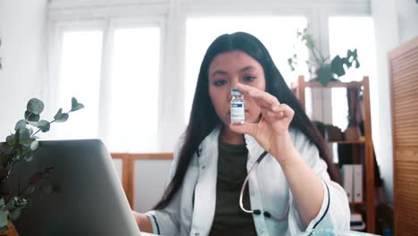 Coronavirus-Impfstoffstudien.-Zoom-in-auf-ernste-junge-Apotheker-Arzt-Frau-im-Labor-Mantel-Blick-auf-Kolben-mit-Medikamenten.