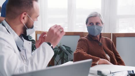 Beautiful-happy-positive-senior-Caucasian-patient-woman-listens-to-doctor-giving-consultation-at-light-clinic-office.