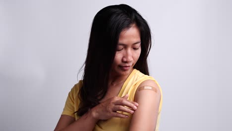 Woman-showing-her-arm-after-getting-vaccinated-with-feeling-happy.-Concept-of-vaccination,-vaccinated-patient,-vaccine-roll-out-program,-Coronavirus,-COVID-19.