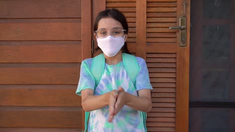 Kleines-Mädchen-immer-bereit-fot-Schule-mit-Handdesinfektionsmittel-und-schützende-Gesichtsmaske-während-Covid-19.