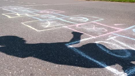 Junge-springt-Spiel-Himmel-und-Hölle-auf-der-Straße.-Close-up-Beine.