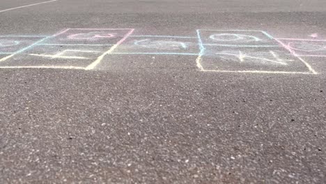 Boy-jumps-playing-hopscotch-in-the-street.-Close-up-legs.-Side-view.