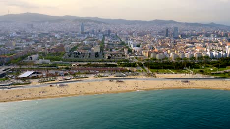 Flying-along-Barcelona-shore-with-city-skyline,-Spain