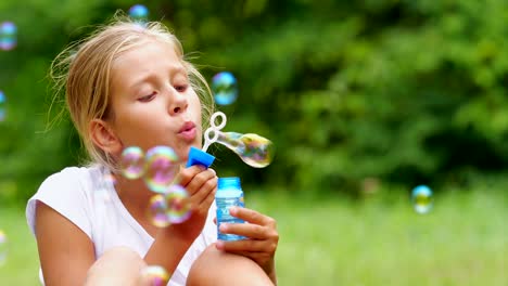 Niña-jugando-con-pompas-de-jabón-al-aire-libre.-Cámara-lenta.