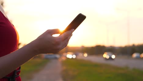 Frau-Hand-mit-Smartphone-gegen-die-Straße-mit-Autos-zu-fahren