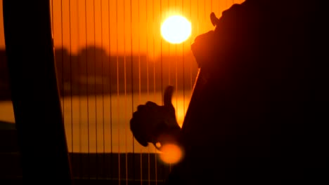 Frauen-Silhouette-spielt-Harfe-bei-Sonnenuntergang