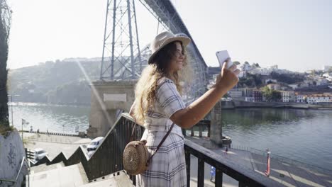 Lady-in-hat-taking-selfie-on-smartphone-on-embankment