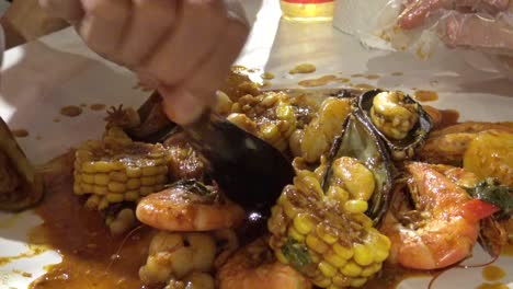 Hervir-de-cubo-de-mariscos-en-salsa-de-especias-de-nueva-orleans-comer-con-la-mano-4k