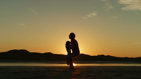 Silhouette-von-Vater-und-Sohn-läuft-auf-einander-am-Strand