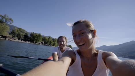 Young-couple-on-Summer-vacation-enjoying-canoe-on-the-lake-in-the-mountains.-People-travel-fun-holidays-concept.-Technology-and-youth-culture-taking-selfie---4K