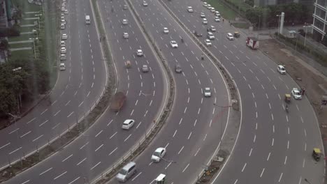 Panoramic-view-of-looking-down-from-a-high-rooftop-to-an-extremely-wide-road-with-passing-traffic-in-an-upcoming-smartcity-in-India