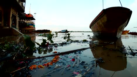 Flood-on-Manikarnika-Ghat-cremation-place-Varanasi-black-coals-branches-float-in-river-boat-on-pier-far-bark-with-firewood-and-gas-crematoria