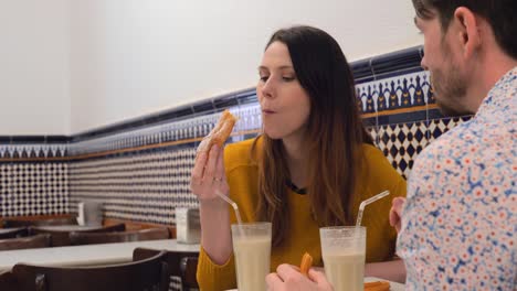 Man-and-woman-drinking-horchata-with-fartons-and-churros